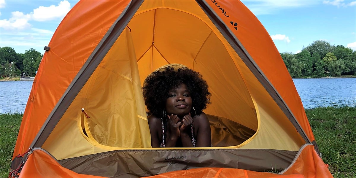 Ein orangefarbenes Zelt, aufgebaut vor einem Fluss.