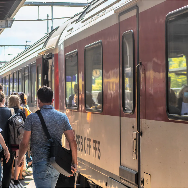 Zug am Perron mit vorbeilaufenden Personen